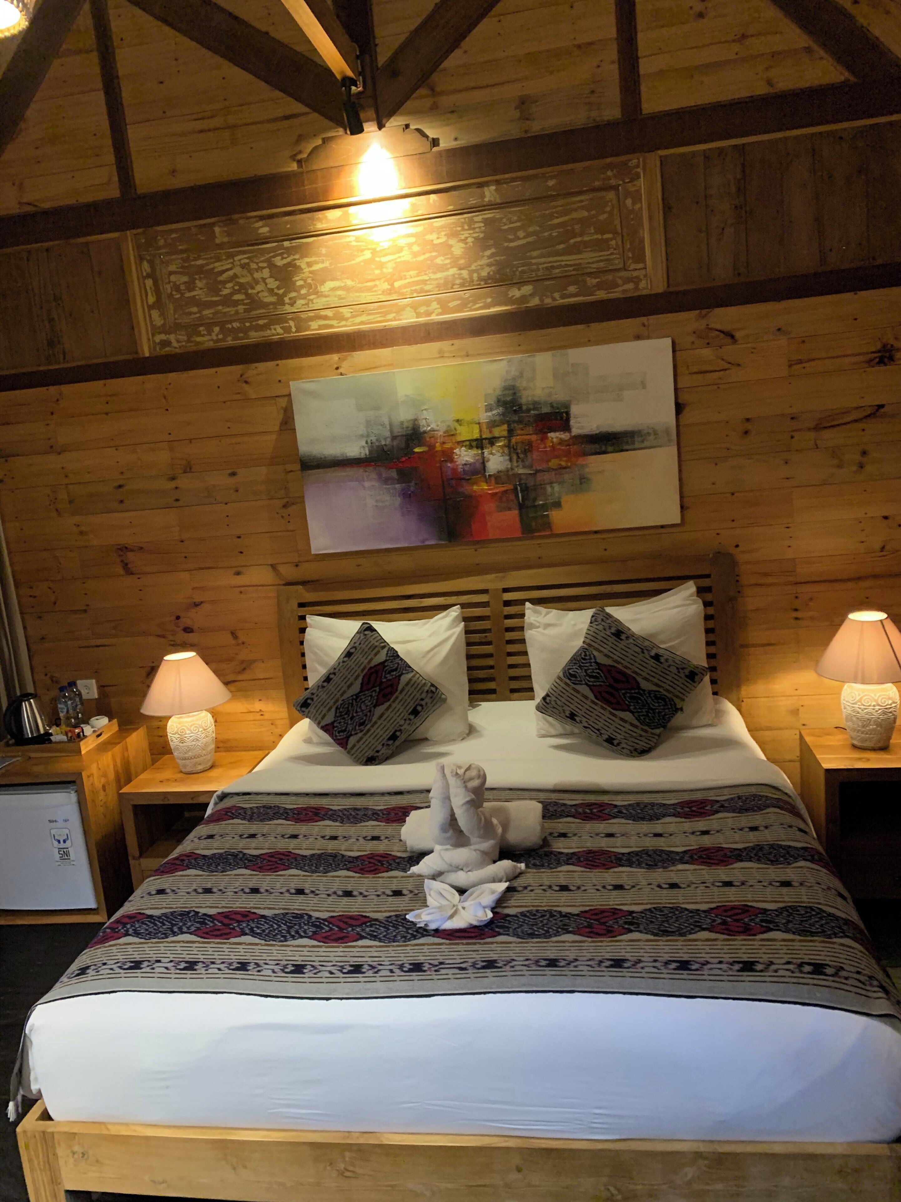Une chambre à coucher de style cabane en bois, avec un grand lit, deux lampes de chevet et un tableau au mur.
