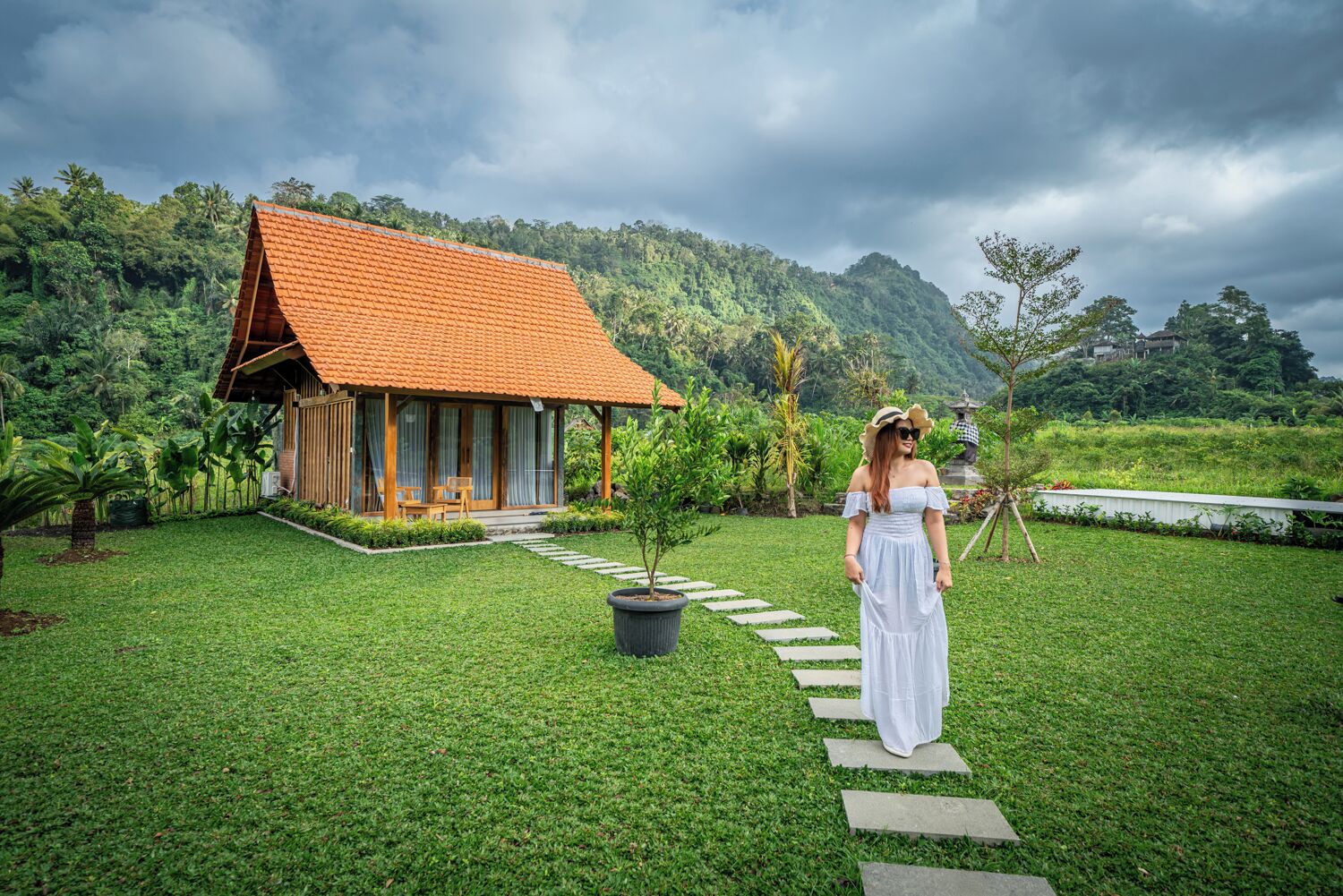 A house with a red roof and a garden with a paved path leading to it.