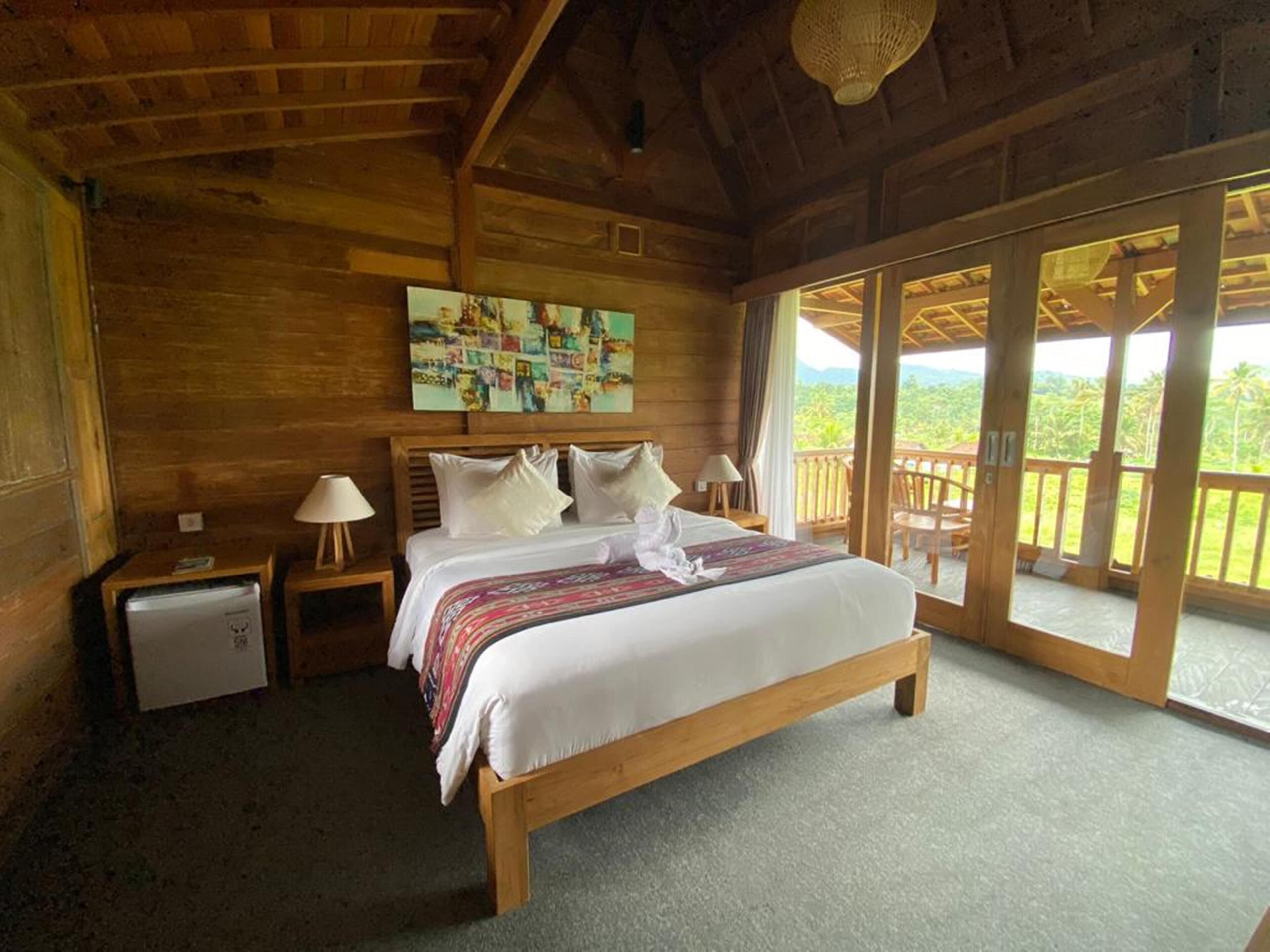 Un dormitorio de cabaña de madera con cama, mesitas de noche y un cuadro en la pared.
