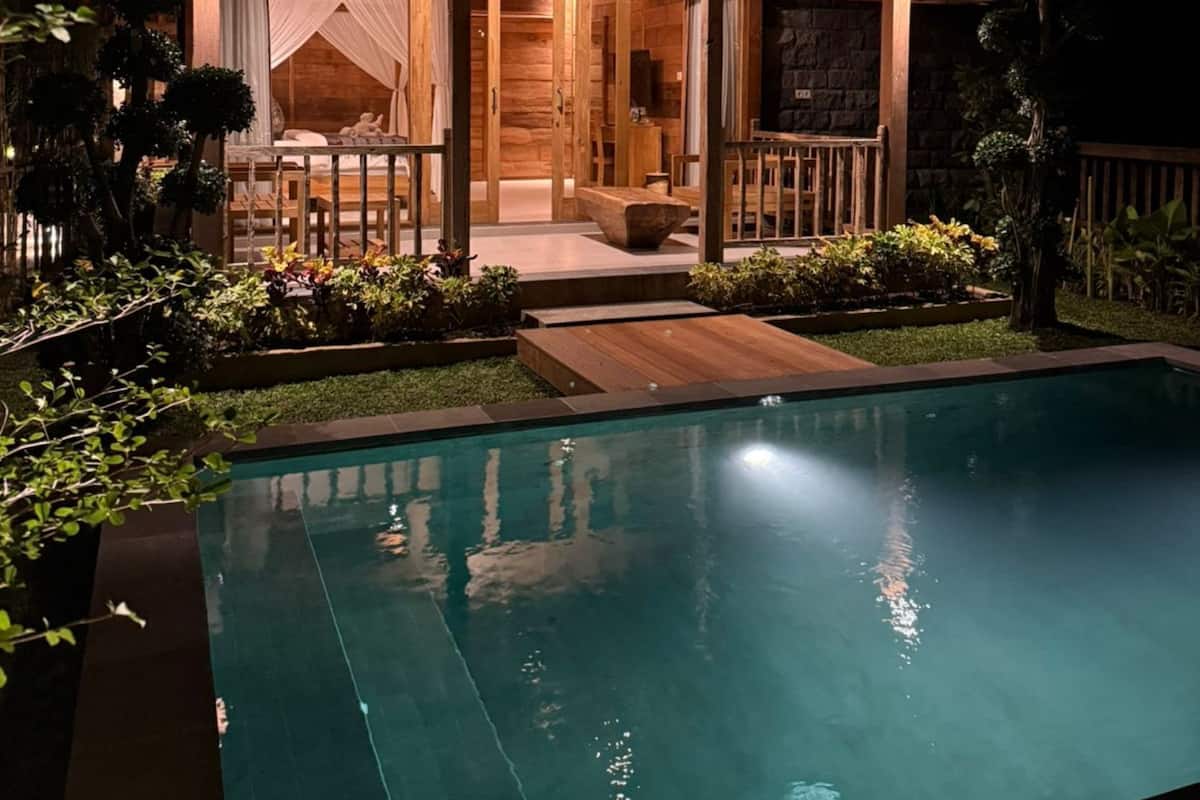 Une maison en bois avec une piscine, de nuit.