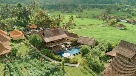 An aerial view of a resort with multiple buildings, a swimming pool, and lush greenery.