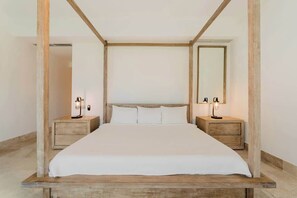 Ein großes Bett mit hölzernem Gestell, zwei Nachttische mit Lampen und ein großer Spiegel an der Wand.