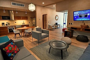 Un salon moderne comprenant un canapé, des fauteuils, une table basse et un téléviseur.