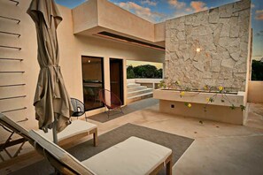 Eine moderne Terrassenausstattung mit Steinmauer, einer Sitzecke mit Tisch und Stühlen sowie einem kleinen Garten mit Blumen.