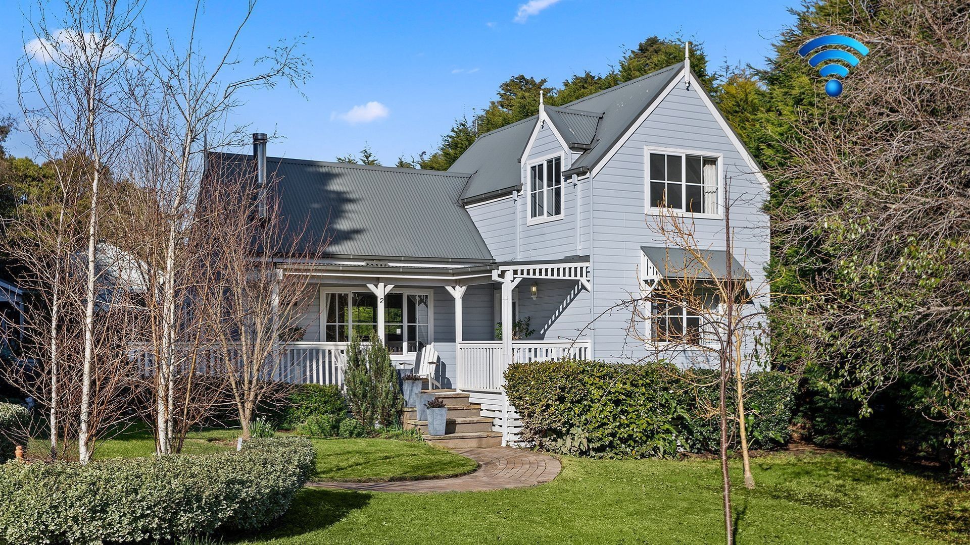 A two-story house with a porch, a chimney, and a garden with a pathway leading to the front door.