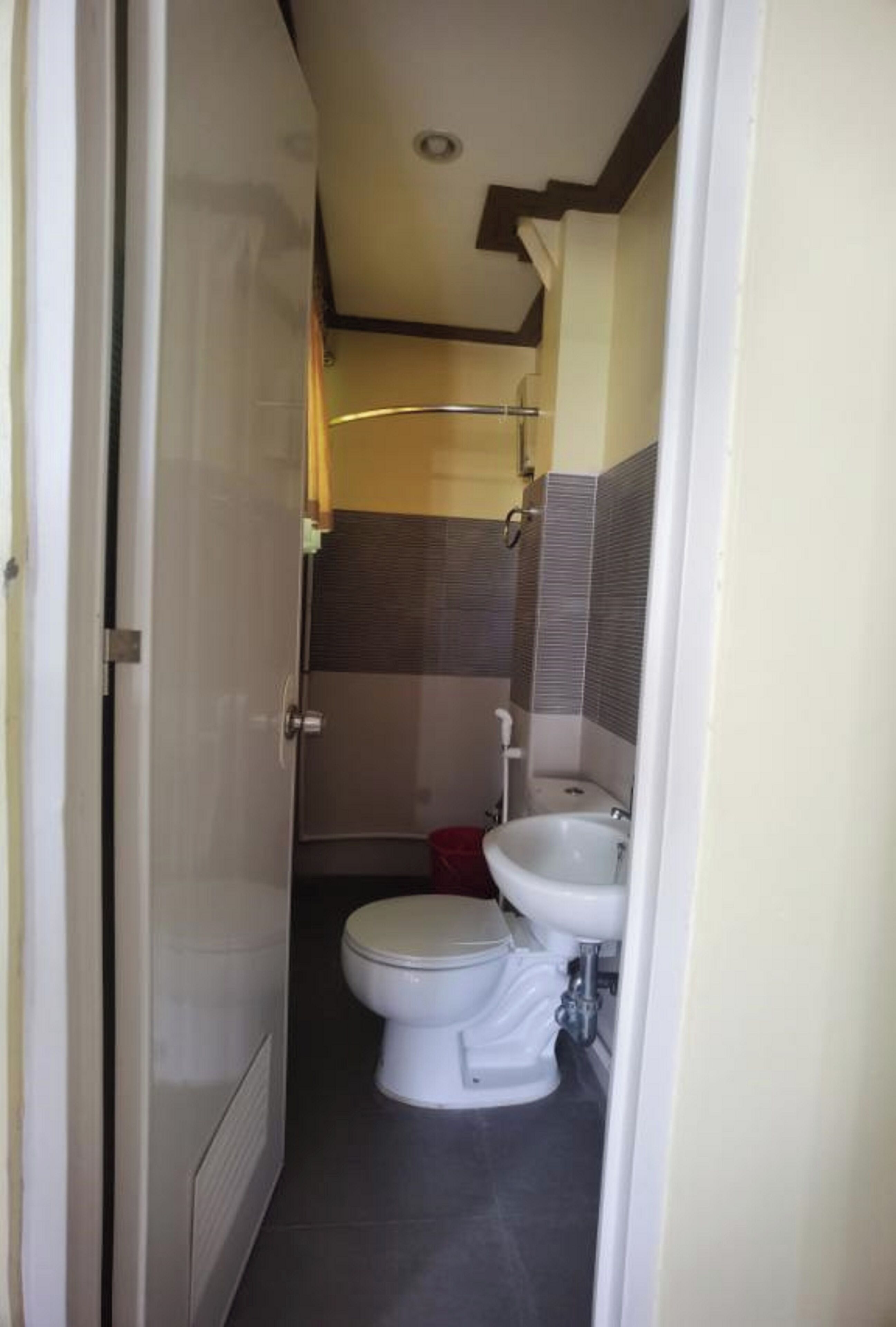 A compact bathroom with a toilet, sink, and shower area.