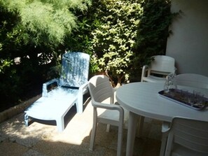 An outdoor patio with a round table and four chairs, surrounded by greenery. - Charming 6-Person Duplex with Garden, Terrace, and Pool Access in Le Grau-du-Roi (Le Grau-du-Roi)