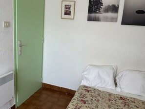 Een kamer met een bed, een deur en een muur met een lijstwerkfoto.