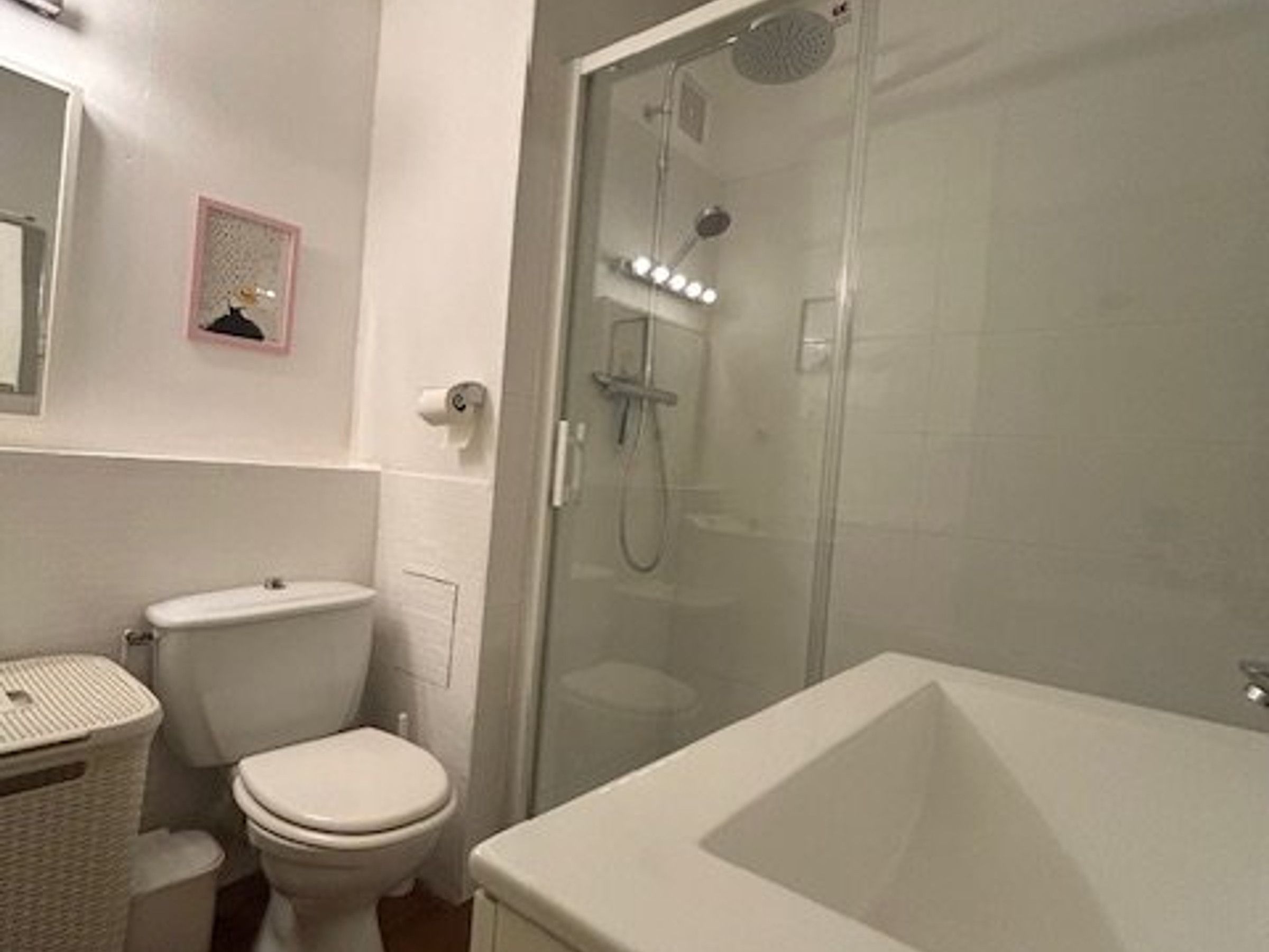 A bathroom with a toilet, a bidet, a glass-enclosed shower, and a white bathtub.
