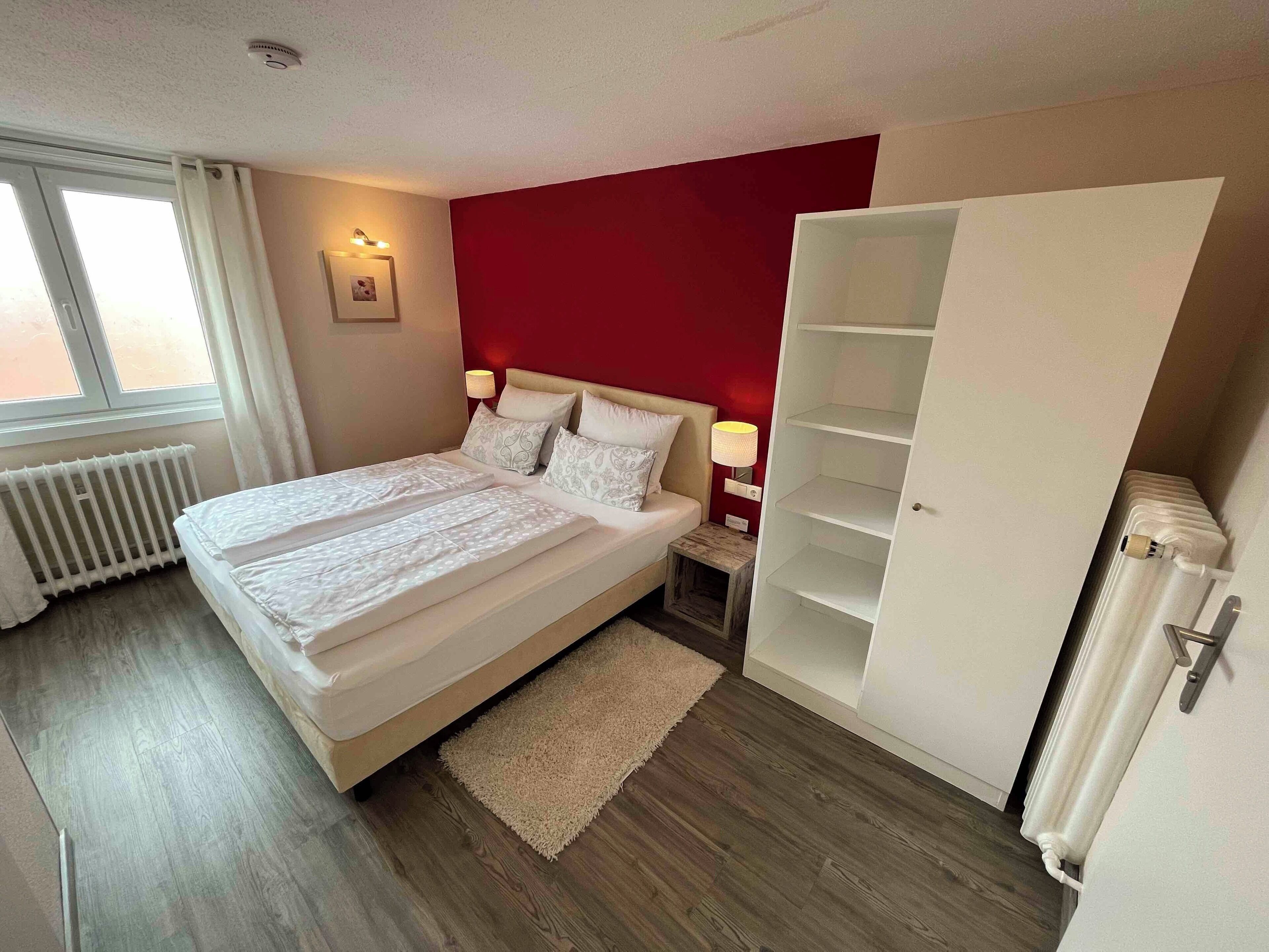 Une chambre à coucher comprenant un lit, une table de chevet, une lampe, un radiateur et une armoire.
