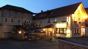 Un hotel con entrada central, un área de estar al aire libre techada y un estacionamiento.
