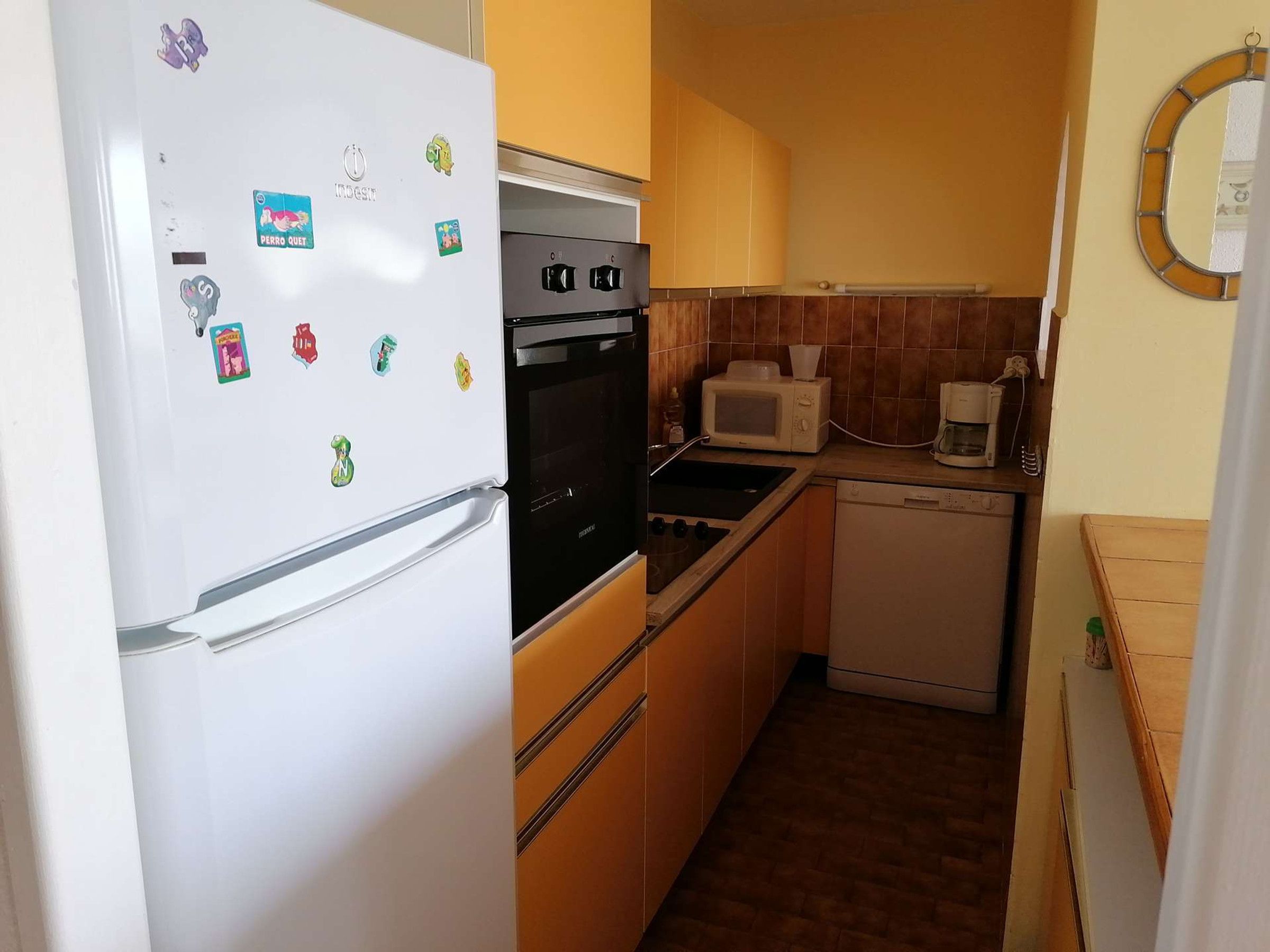 Eine kompakte Küche mit Kühlschrank, Backofen, Mikrowelle und Geschirrspüler.