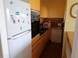 A compact kitchen with a refrigerator, oven, microwave, and dishwasher. - Direct beach access, 3 rooms, 6 beds, private parking (Port Camargue)