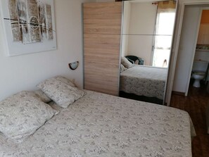 A bedroom with a bed, a mirror, and a door leading to a bathroom. - Direct beach access, 3 rooms, 6 beds, private parking (Port Camargue)