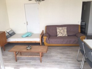 A compact living space with a sofa, a small bed, a table, and a door. - 2-room apartment, sleeps 5 with pool and parking in Port Camargue (Port Camargue)