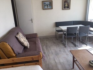 A room with a sofa, a wooden table, a bench, and a dining area with chairs. - 2-room apartment, sleeps 5 with pool and parking in Port Camargue (Port Camargue)