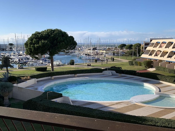 A swimming pool with a view of a marina and a building with a modern design.