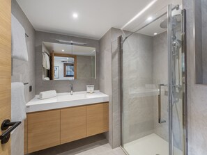 Un bagno moderno con doccia vetrata, uno specchio grande e un mobile vanitario in legno.