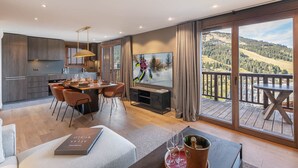 Una sala de estar moderna con un televisor grande, un comedor y un balcón con vistas panorámicas.