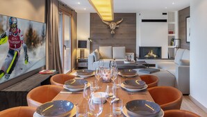 Una sala de estar moderna con comedor, chimenea y un cuadro grande de un esquiador.