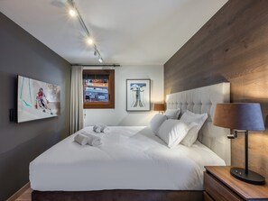 Una camera d'albergo moderna con un letto grande, una testiera in legno, un comodino, una lampada e due quadri appesi al muro.