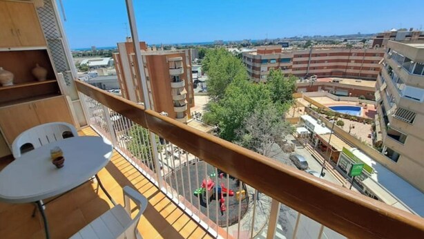 Un balcon offrant une vue sur le paysage urbain, avec des bâtiments et un espace piscine.