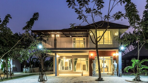 Une maison moderne à deux étages, dotée d’un balcon, de grandes fenêtres et d’une entrée bien éclairée.