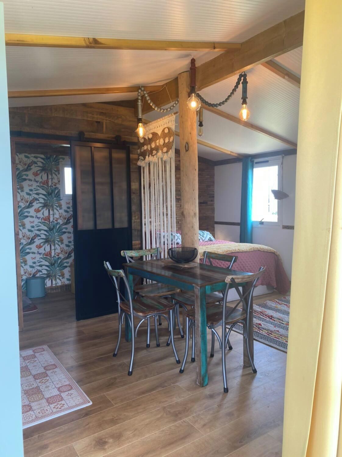 A cozy room with a wooden dining table, chairs, and a hanging light fixture.