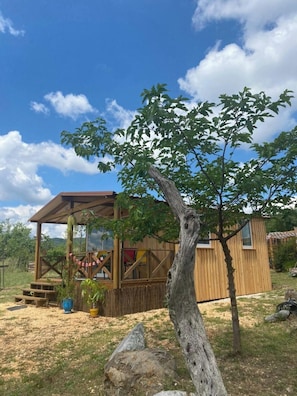 A wooden cabin with a glass enclosure, surrounded by a natural landscape.