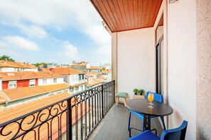 Un balcon avec une table et des chaises, un pot de fleurs et une vue sur le paysage urbain.