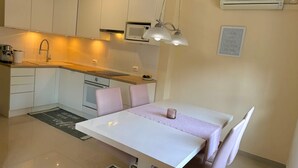 Eine moderne Küche mit weißen Schränken, einer eingebauten Mikrowelle und einem Essbereich mit weißem Tisch und Stühlen.