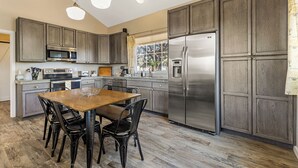 Una cocina moderna con alacenas de madera oscura, electrodomésticos de acero inoxidable y una mesa de comedor de madera con sillas.