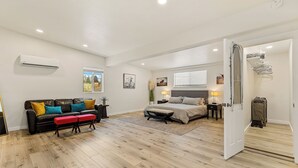 Un dormitorio amplio con una cama grande, una zona de estar con sofá y banco, y un vestidor.