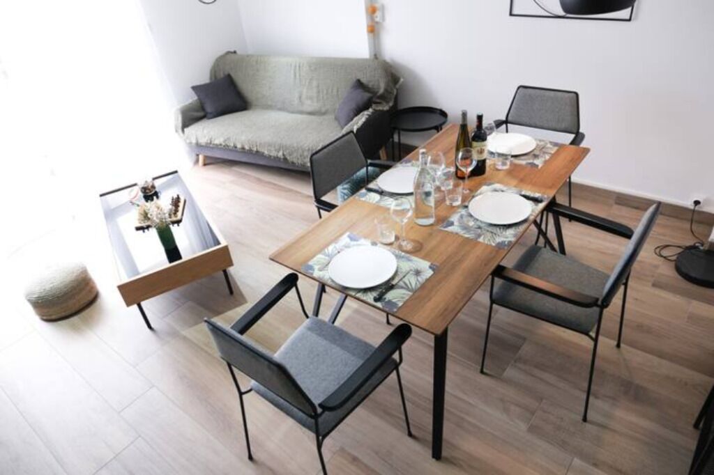 A dining area with a wooden table set for four, surrounded by modern chairs.