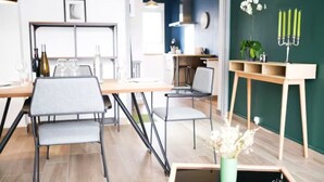 Un comedor moderno con una mesa de madera, dos sillas y una mesita auxiliar con un florero.