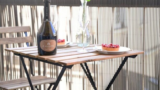 A bottle of C. G. Grey wine on a wooden table with a glass and a plate of raspberries.