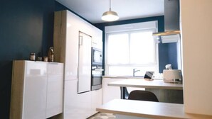 A compact kitchen with white cabinets, a built-in oven, and a window providing natural light.