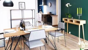 A modern dining area with a wooden table set for four, surrounded by grey chairs.