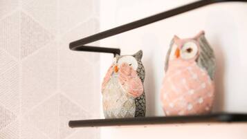Two decorative owls on a shelf against a patterned wall.