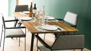 A dining area with a wooden table, metal chairs, and a flat-screen TV mounted on the wall.