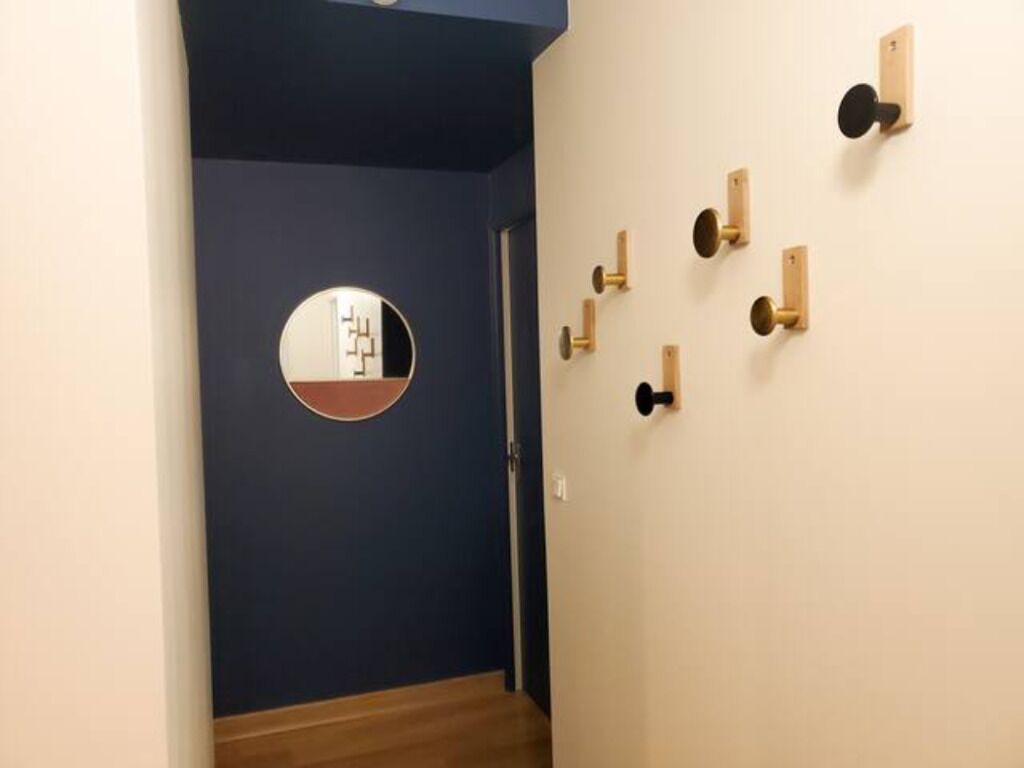 A hallway with a blue wall, a wooden floor, and a circular mirror.