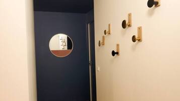 A hallway with a blue wall, a wooden floor, and a circular mirror.