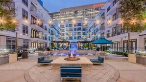 A hotel courtyard with a central fire feature, outdoor seating, and a fountain. - Relax at Cityline I Premium 2BR in Dallas (Richardson)