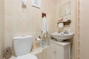 A bathroom with a toilet, sink, and cabinet.