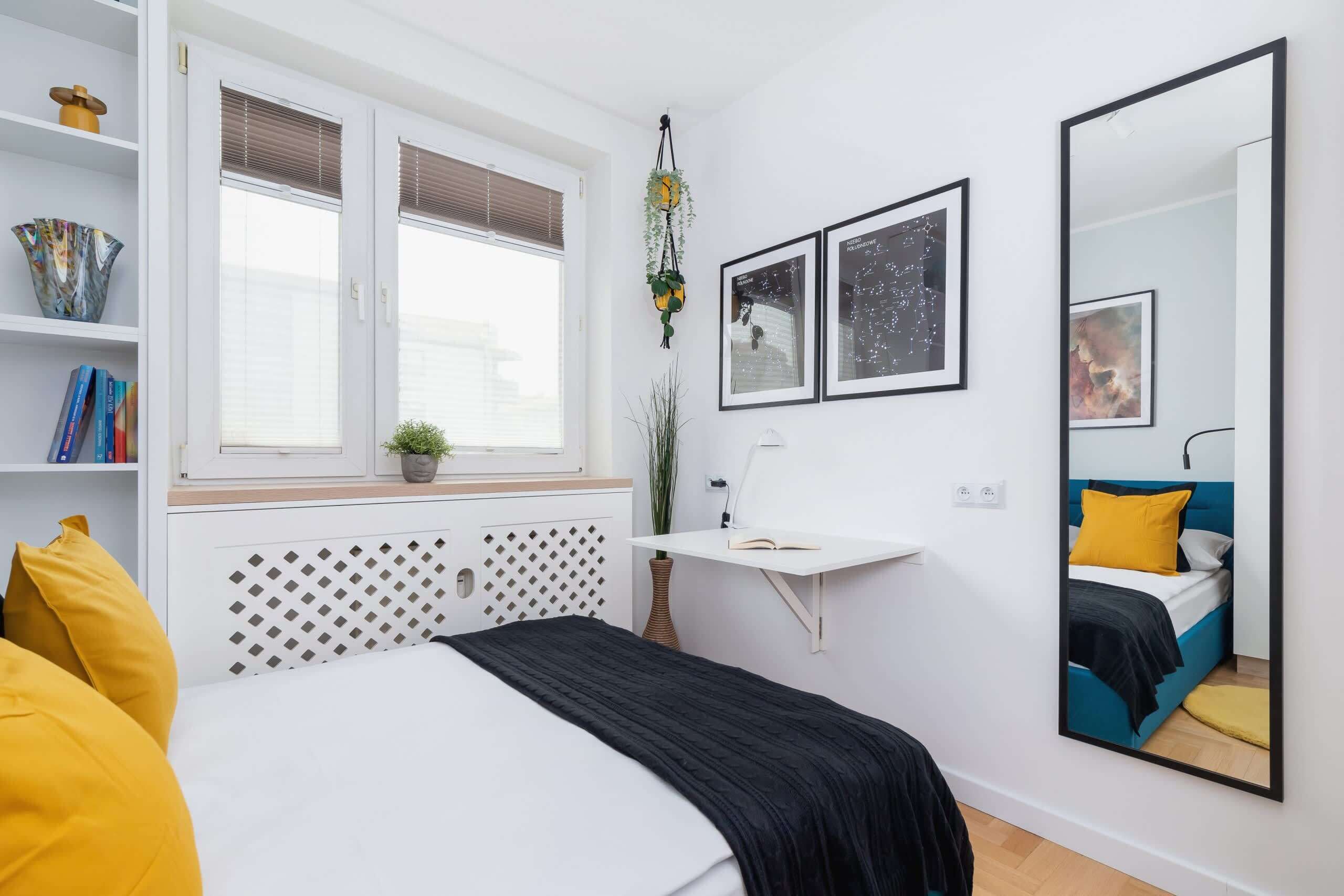 Un dormitorio moderno con cama, mesita de noche y un espejo grande.