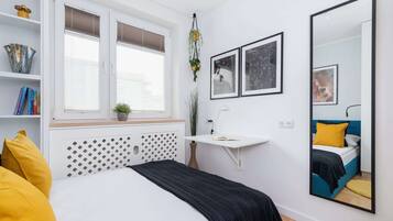 Un dormitorio moderno con cama, mesita de noche y un espejo grande.