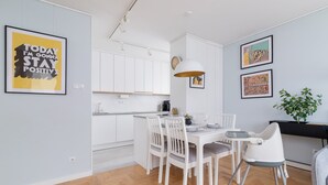 A modern kitchen with white cabinets, a dining table with chairs, and a small dining area with a high chair.
