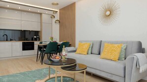 A modern living room with a grey sofa, a round coffee table, and a dining area with a table and chairs.
