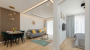 A modern living room with a dining area, a sofa, and a TV.
