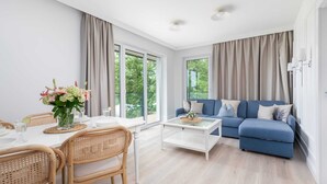 Una sala de estar moderna con un sofá azul, una mesa de comedor con sillas y una mesita de centro.